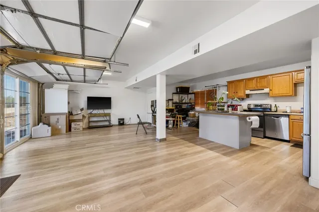 a kitchen with stainless steel appliances kitchen island granite countertop a stove top oven a sink dishwasher a dining table and chairs with wooden floor