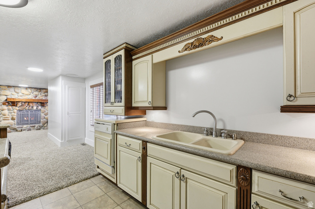 2342 Charros Road Sandy, UT 84092 - Photo 46 of 94 Kitchen area featuring cream cabinetry with decorative wood accents, a double basin sink, and speckle-patterned countertops