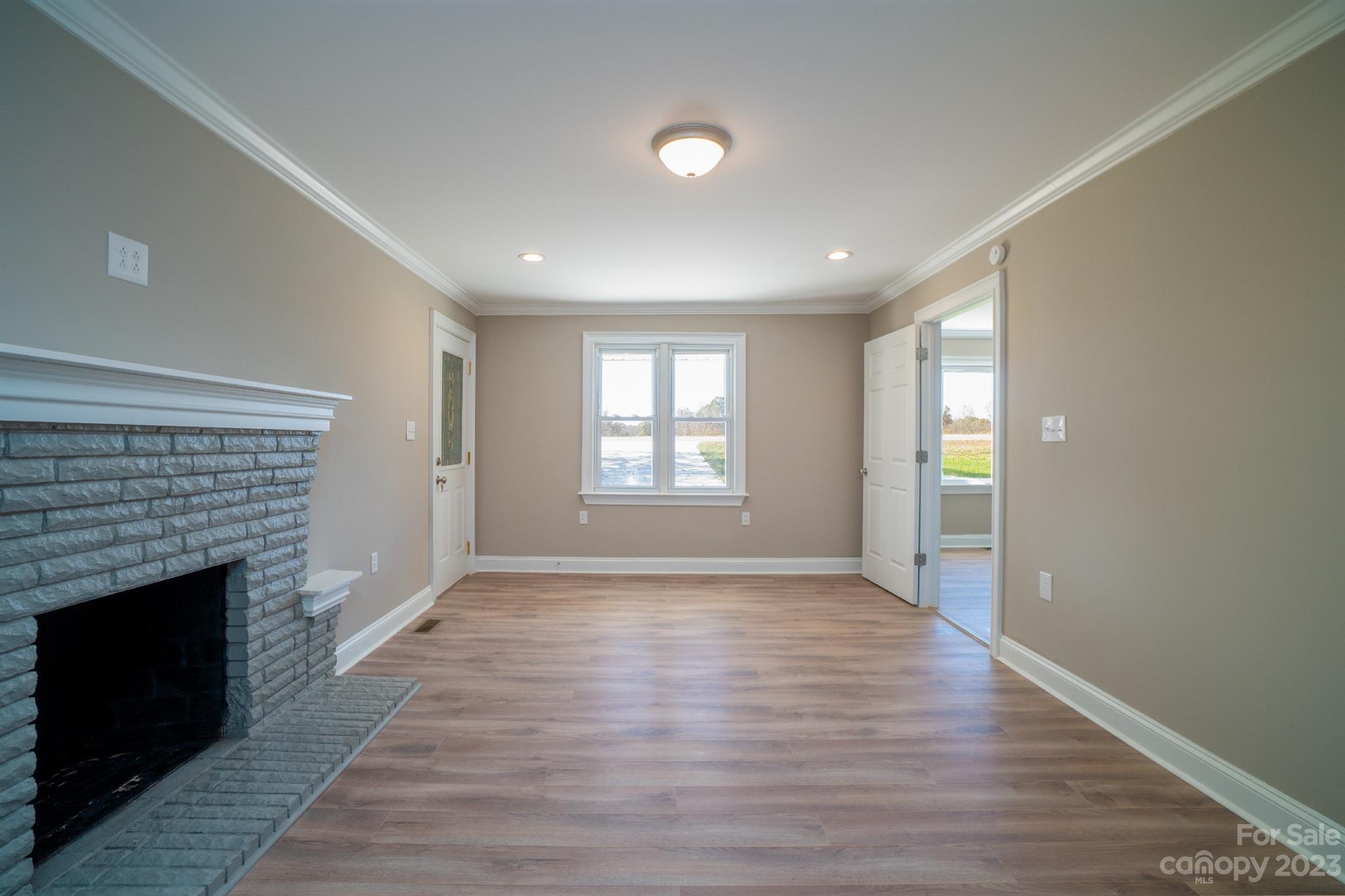 446 Rash Road Olin, NC 28660 - Photo 8 of 35 an empty room with wooden floor fireplace and windows