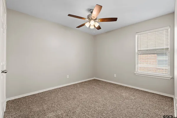 an empty room with a window and a ceiling fan