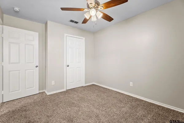 an empty room with closet and a chandelier fan