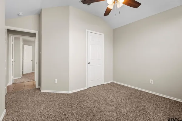 an empty room with a ceiling fan and carpet