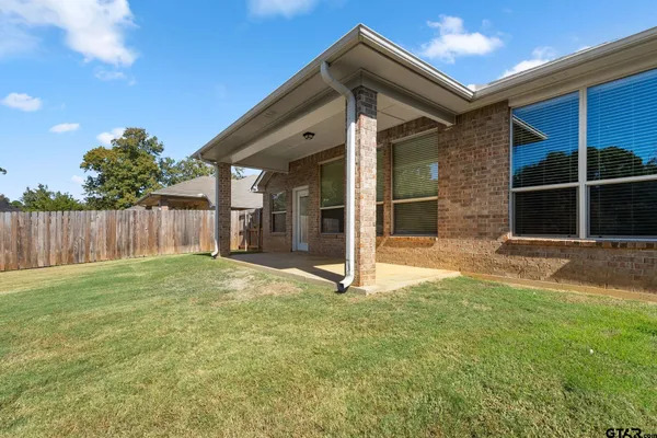 a view of a house with large windows and a big yard with wooden fence