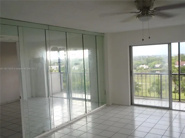 an empty room with chandelier fan and window