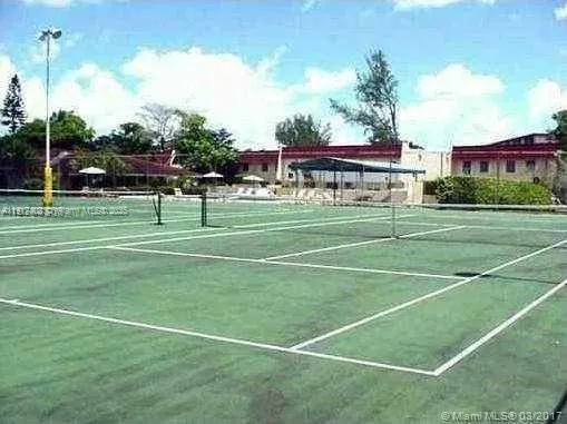a view of a tennis ground with large trees