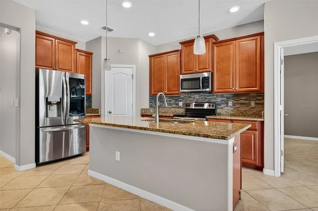 a kitchen with stainless steel appliances granite countertop a refrigerator a stove a sink and a microwave