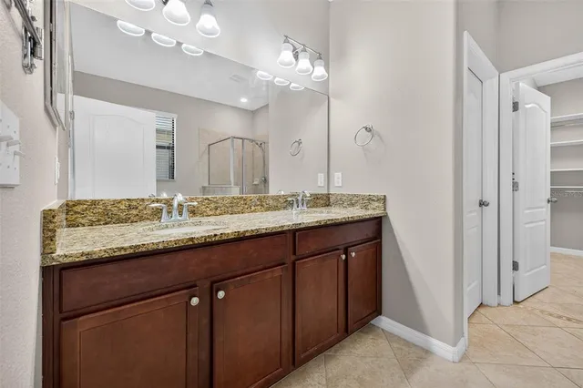 a bathroom with a granite countertop double vanity sink and a mirror