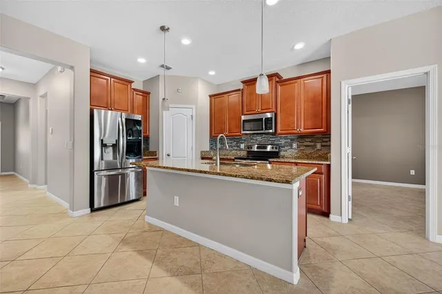 a kitchen with stainless steel appliances kitchen island granite countertop a refrigerator and a stove top oven