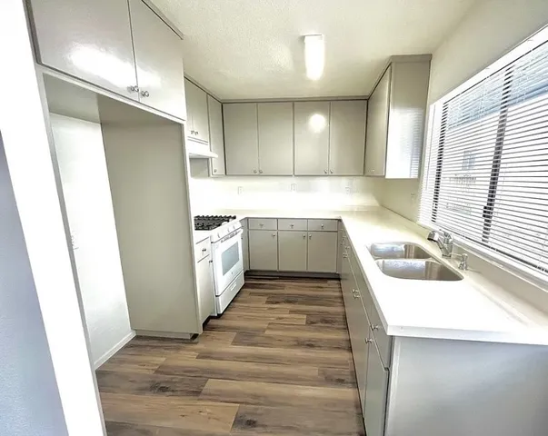 an empty room with wooden floor staircase and windows