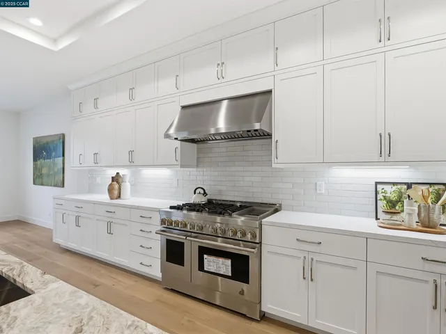 a kitchen that has a lot of cabinets a sink a stove and wooden floors