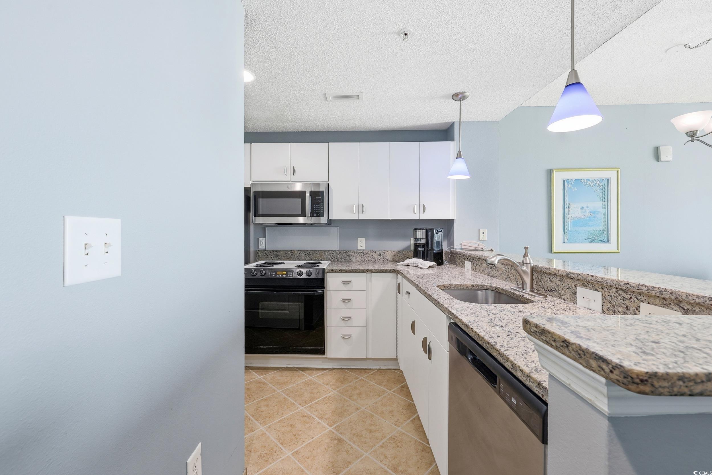 300 North Ocean Boulevard, Unit 1608 North Myrtle Beach, SC 29582 - Photo 14 of 30 Kitchen featuring stainless steel appliances, a peninsula, hanging light fixtures, white cabinets, and light tile patterned floors