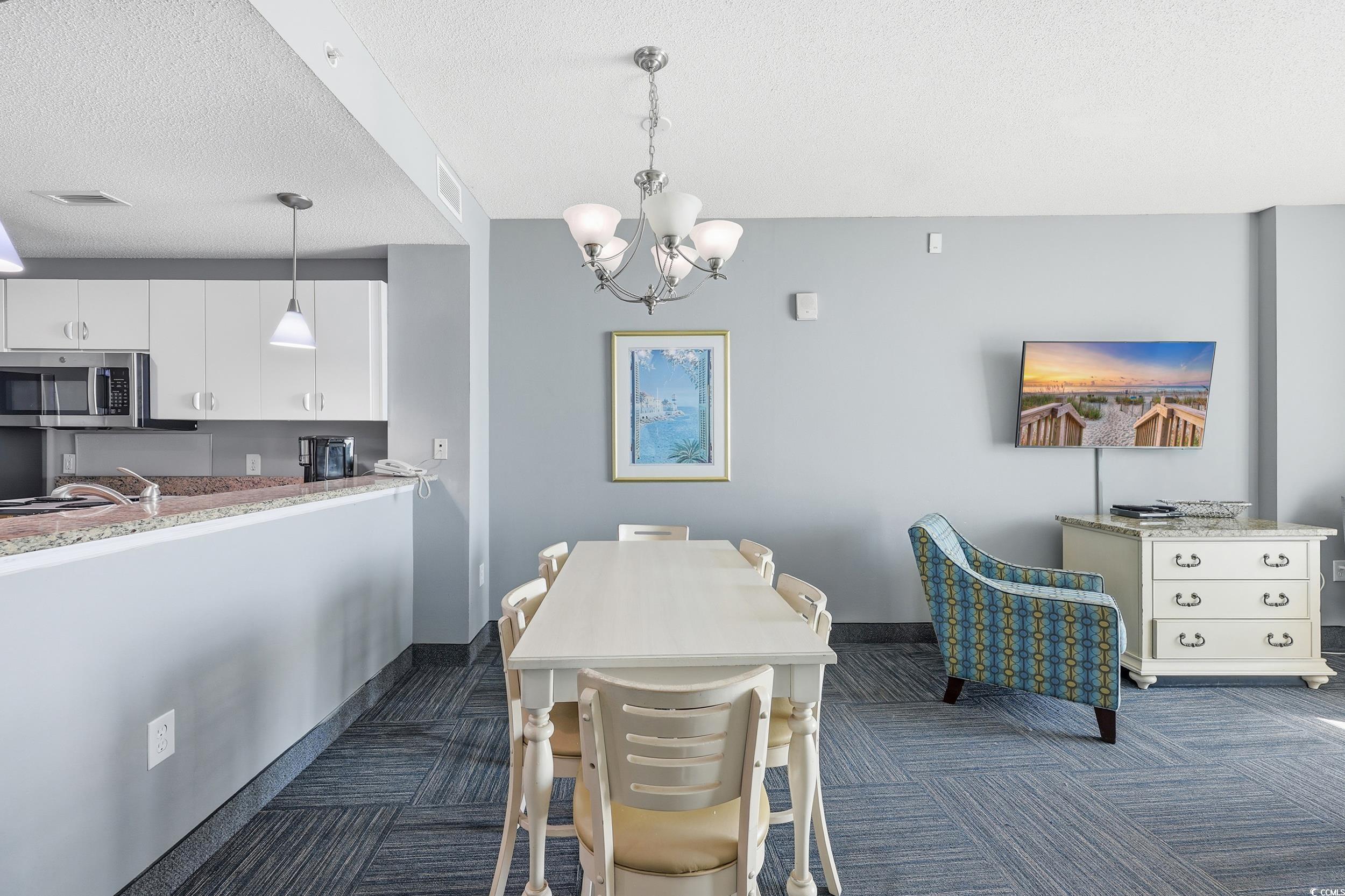 300 North Ocean Boulevard, Unit 1608 North Myrtle Beach, SC 29582 - Photo 9 of 30 Dining area with a chandelier, a textured ceiling, and dark carpet
