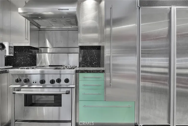 a kitchen with stainless steel appliances granite countertop a refrigerator a stove and white cabinets with wooden floors