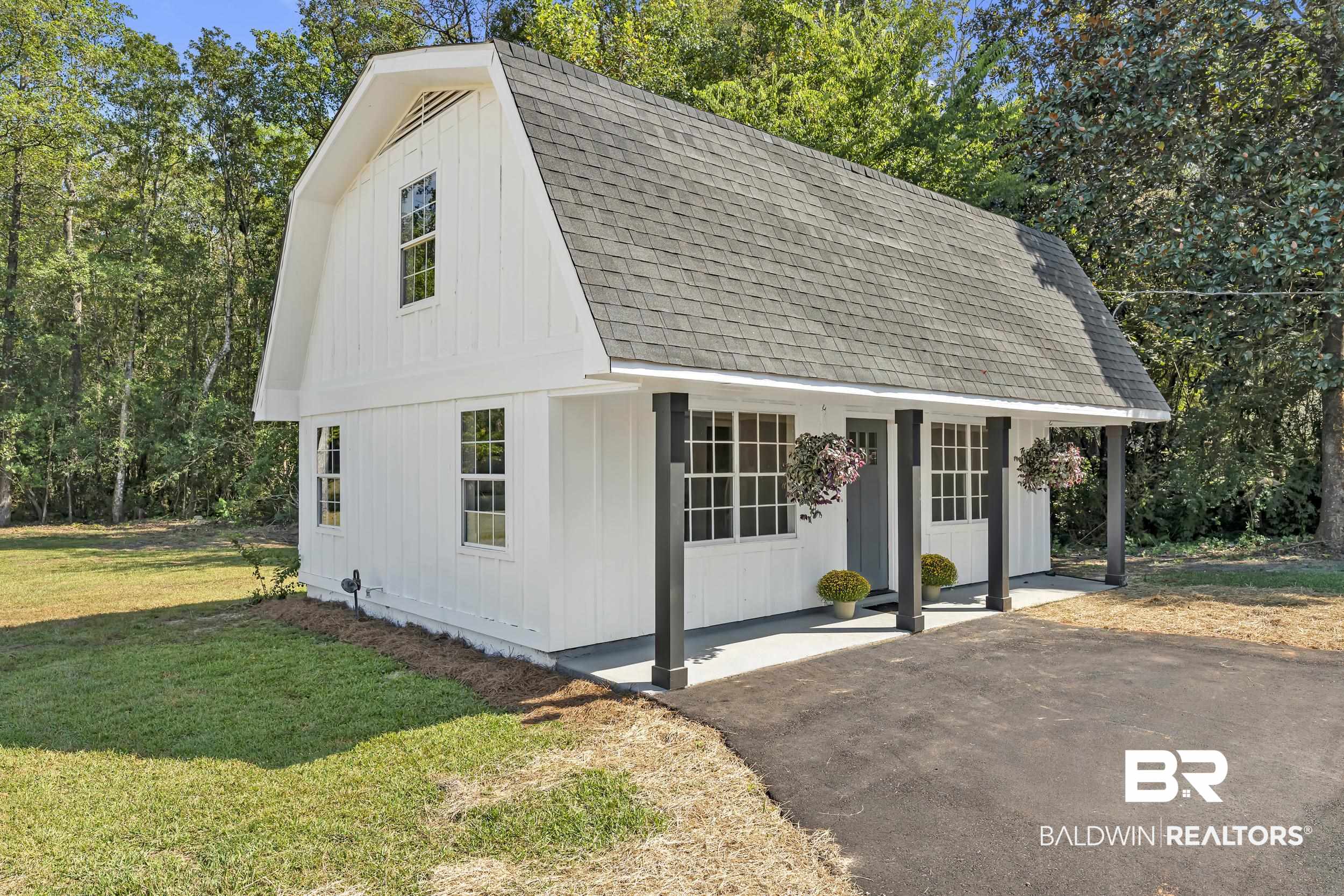 8351 Theodore Dawes Road Theodore, AL 36582 - Photo 27 of 46 View of front facade with a gambrel roof, a shingled roof, covered porch, a front lawn, and an outdoor structure