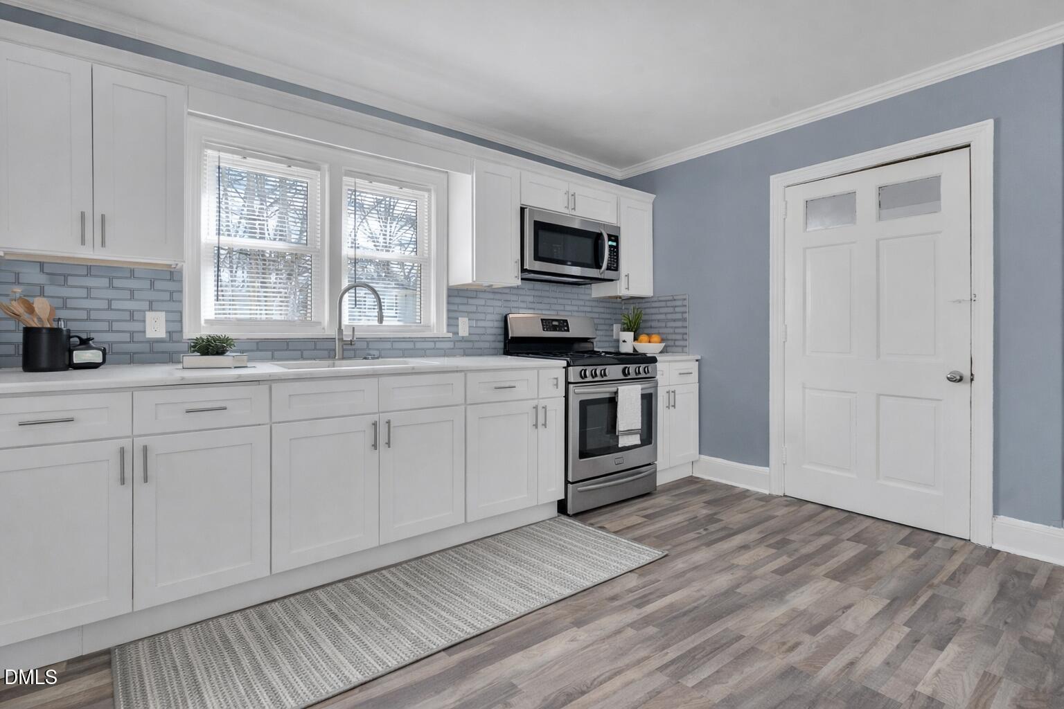 134 Nelson Street Durham, NC 27707 - Photo 13 of 25 a kitchen with stainless steel appliances granite countertop a stove a sink and white cabinets