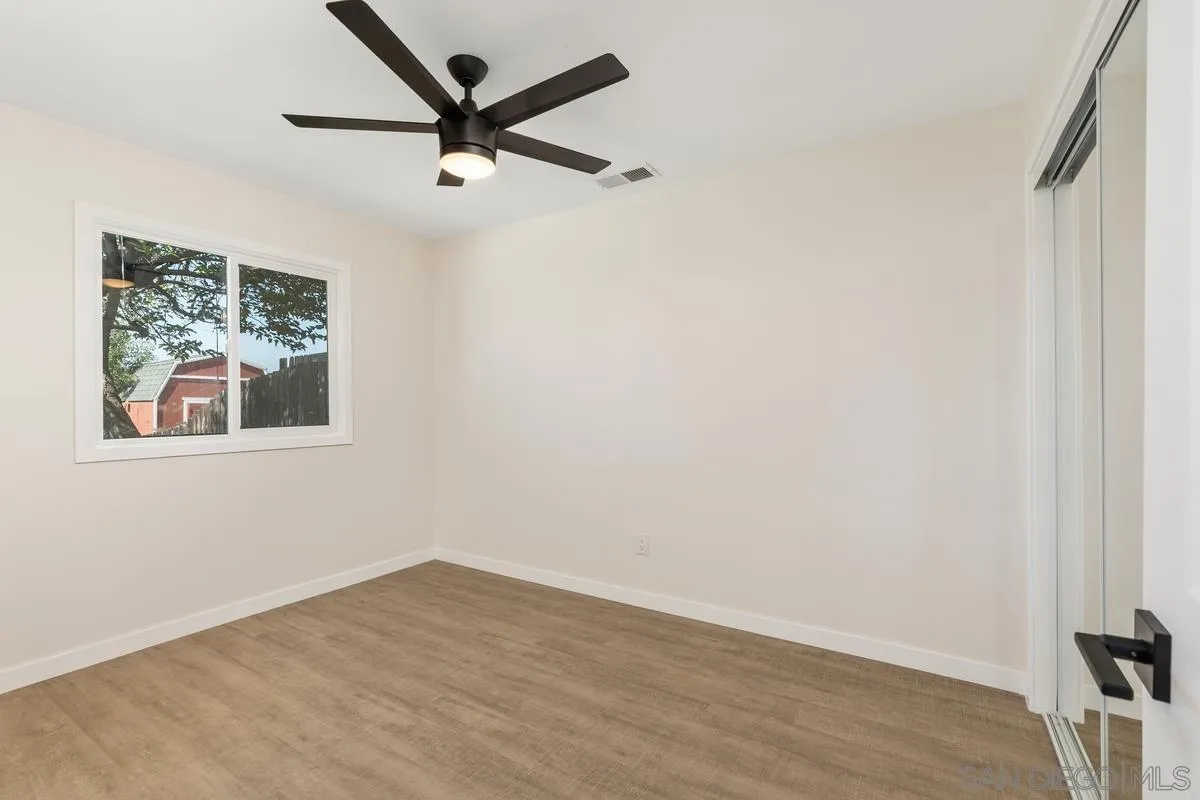 9257 Ruffin Road Santee, CA 92071 - Photo 16 of 28 an empty room with wooden floor and a ceiling fan