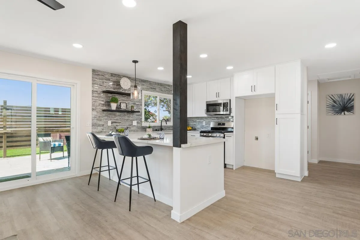 9257 Ruffin Road Santee, CA 92071 - Photo 3 of 28 a kitchen with stainless steel appliances kitchen island granite countertop a refrigerator oven a sink a dining table and chairs with wooden floor