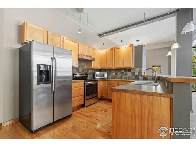 a kitchen with stainless steel appliances granite countertop a refrigerator a sink a stove and oven