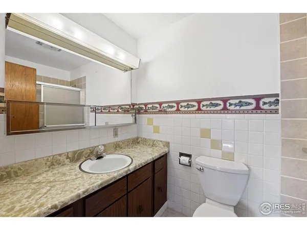 a bathroom with a granite countertop sink a toilet a mirror and shower