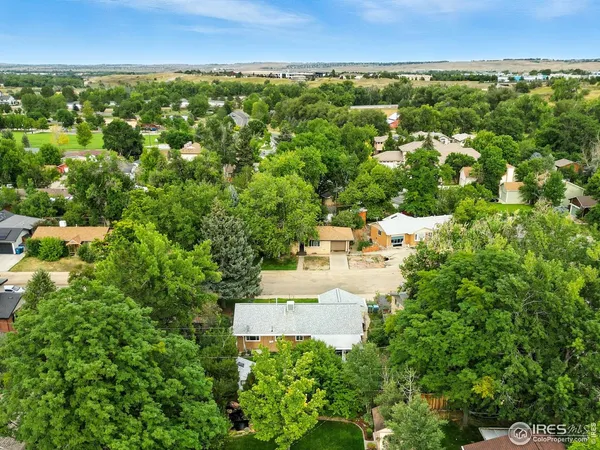 an aerial view of residential houses with outdoor space and trees all around