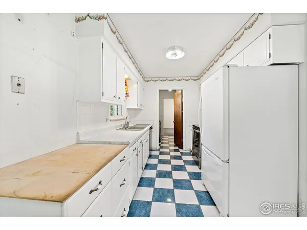 a kitchen with a sink a refrigerator and white cabinets