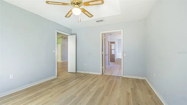 an empty room with wooden floor closet and windows