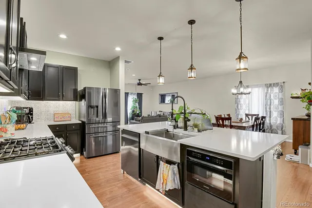 a kitchen with kitchen island a stove a sink a refrigerator and chairs