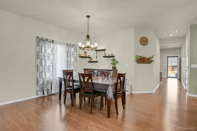 a view of a dining room and livingroom with furniture wooden floor a chandelier