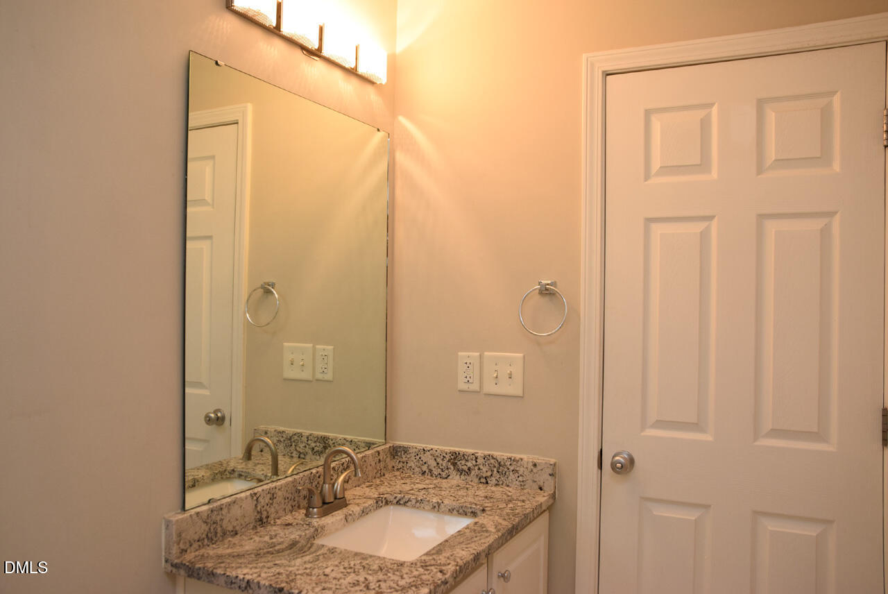 8269 City Loft Court Raleigh, NC 27613 - Photo 21 of 26 a bathroom with a granite countertop sink and a mirror