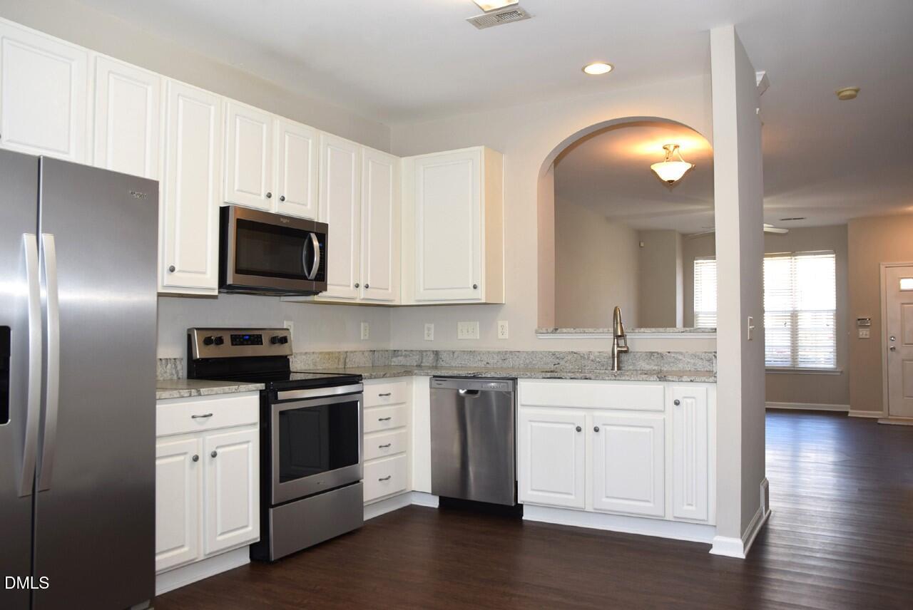 8269 City Loft Court Raleigh, NC 27613 - Photo 7 of 26 a kitchen with granite countertop a sink stainless steel appliances and white cabinets