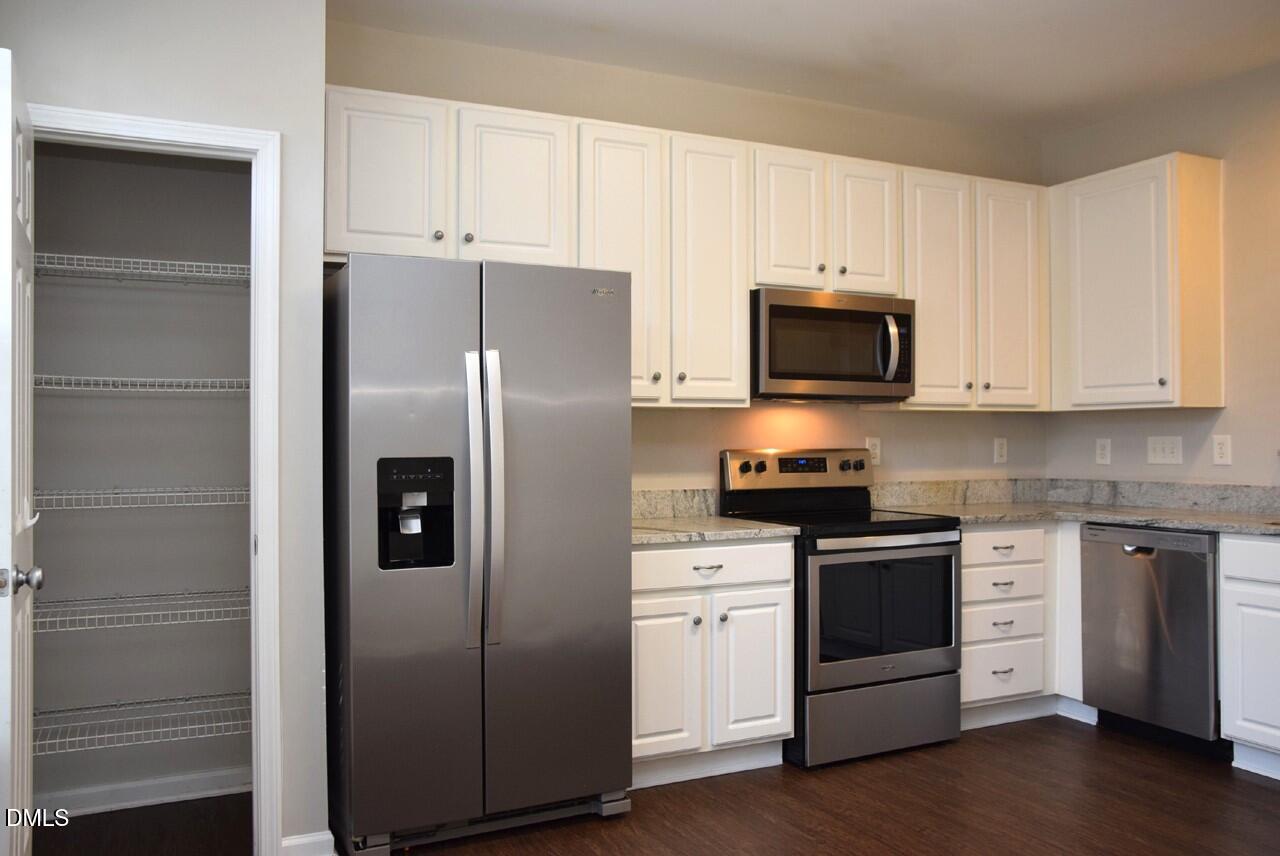 8269 City Loft Court Raleigh, NC 27613 - Photo 8 of 26 a kitchen with stainless steel appliances white cabinets and a refrigerator