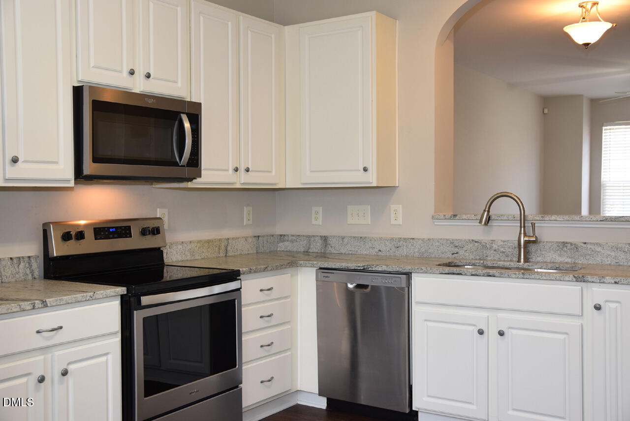 8269 City Loft Court Raleigh, NC 27613 - Photo 10 of 26 a kitchen with granite countertop white cabinets and stainless steel appliances