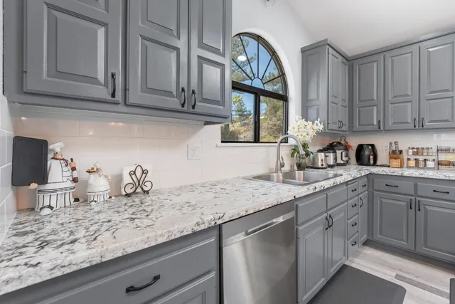 a kitchen with granite countertop stainless steel appliances a sink and cabinets