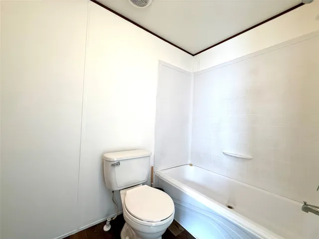 a white toilet sitting next to a bath tub and a shower