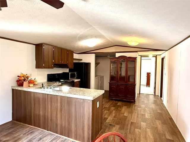 a kitchen with kitchen island granite countertop a stove top oven a sink and dishwasher with wooden floor