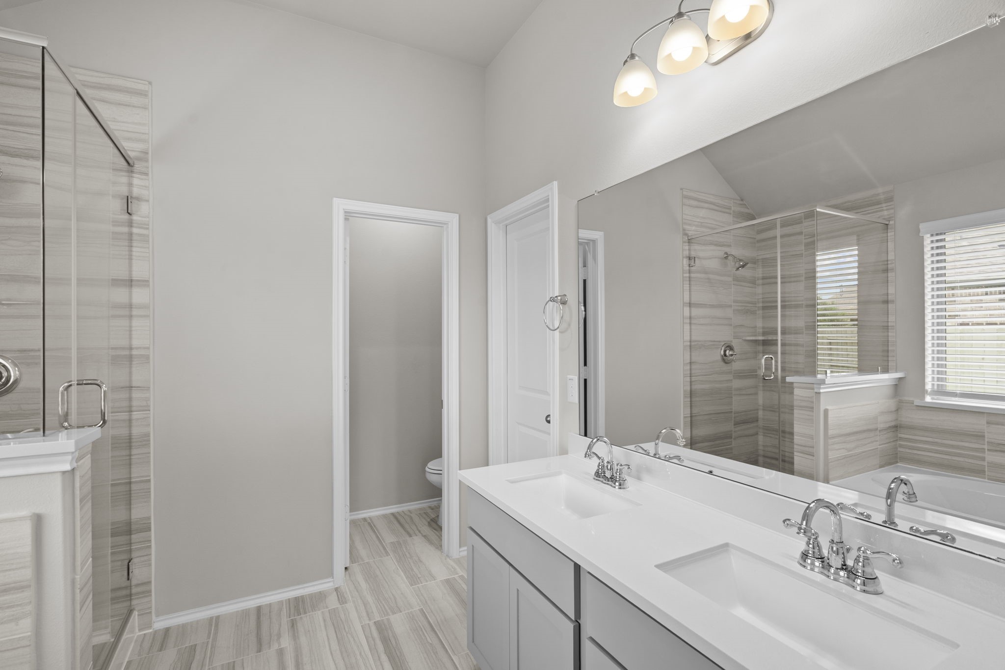 2011 Oak Leaf Court Manvel, TX 77578 - Photo 18 of 28 This bathroom features a modern design with a double vanity, large mirror, and stylish lighting. It includes a spacious glass-enclosed shower and neutral tile flooring, offering a bright and elegant space.