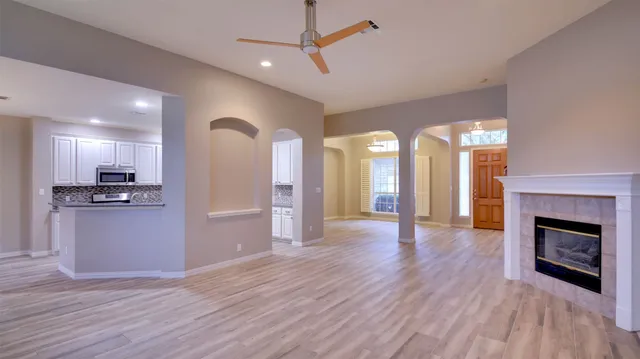 a view of an empty room with wooden floor and a kitchen