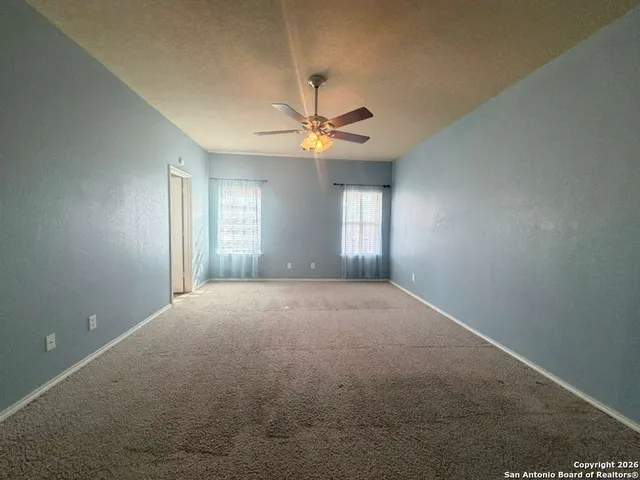 a view of an empty room with window and chandelier fan