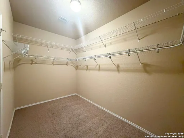 an empty room with a chandelier fan and a window