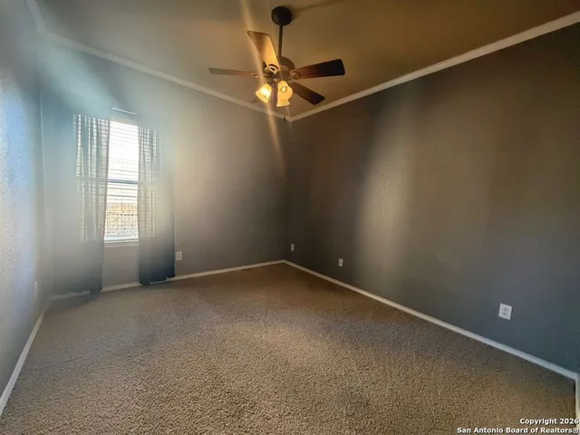 an empty room with a chandelier fan and windows