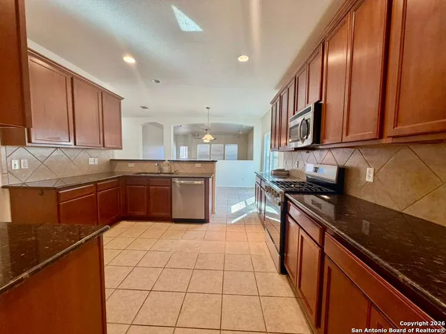 a kitchen with granite countertop a stove a sink and a refrigerator