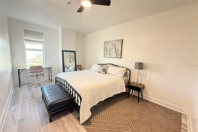 a bedroom with a bed a lamp on desk and a window