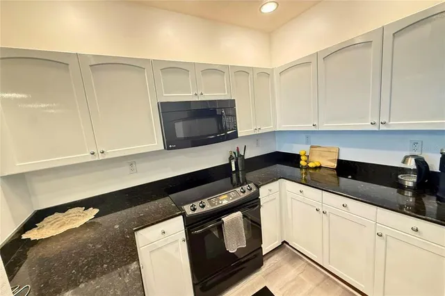 a kitchen with granite countertop white cabinets and black appliances