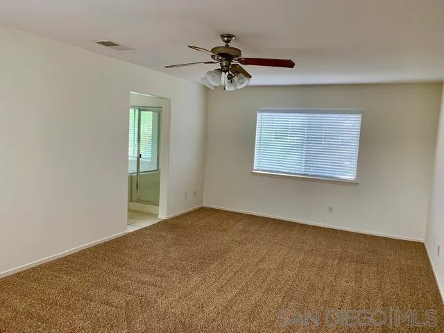6921 Catamaran Drive Carlsbad, CA 92011 - Photo 3 of 26 an empty room with a chandelier fan and windows