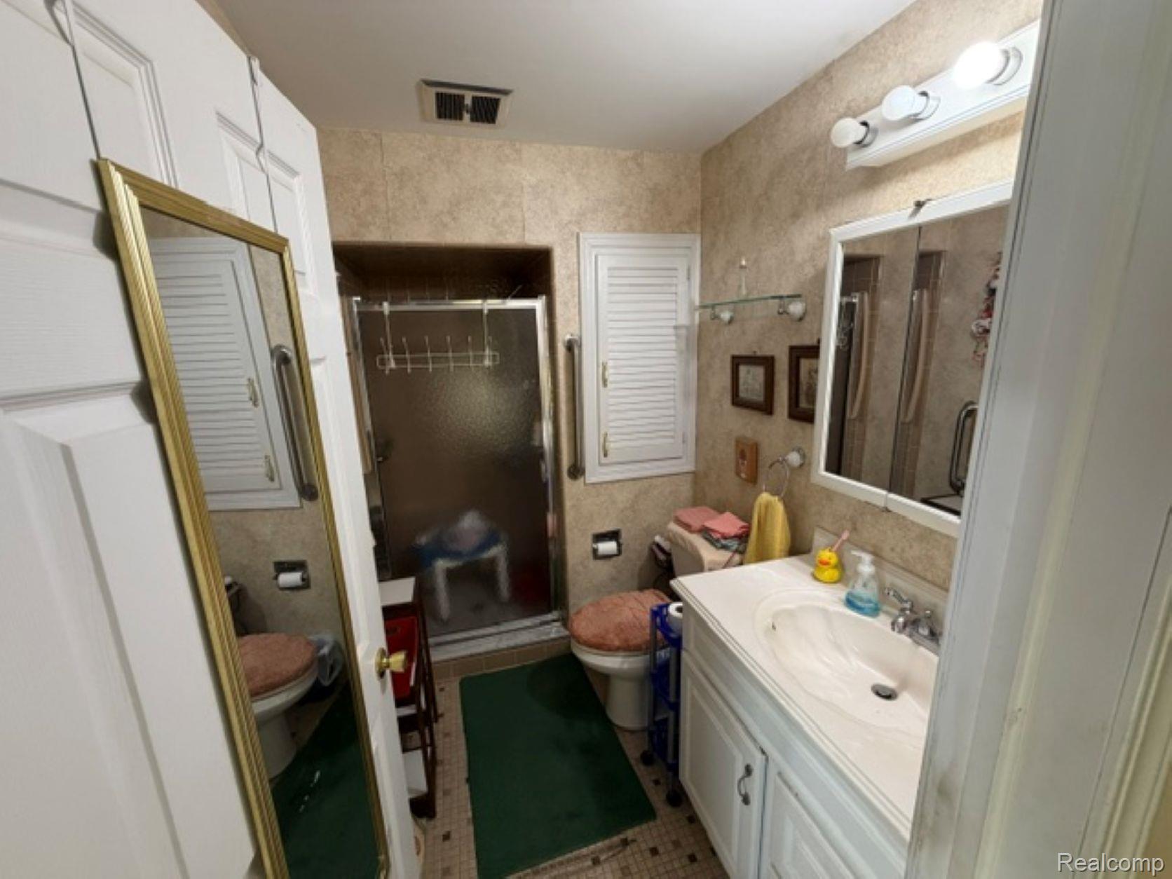 53151 Fairchild Road Macomb, MI 48042 - Photo 19 of 22 Bathroom featuring a white vanity with integrated sink, an illuminated mirrored medicine cabinet, and a glass-enclosed shower