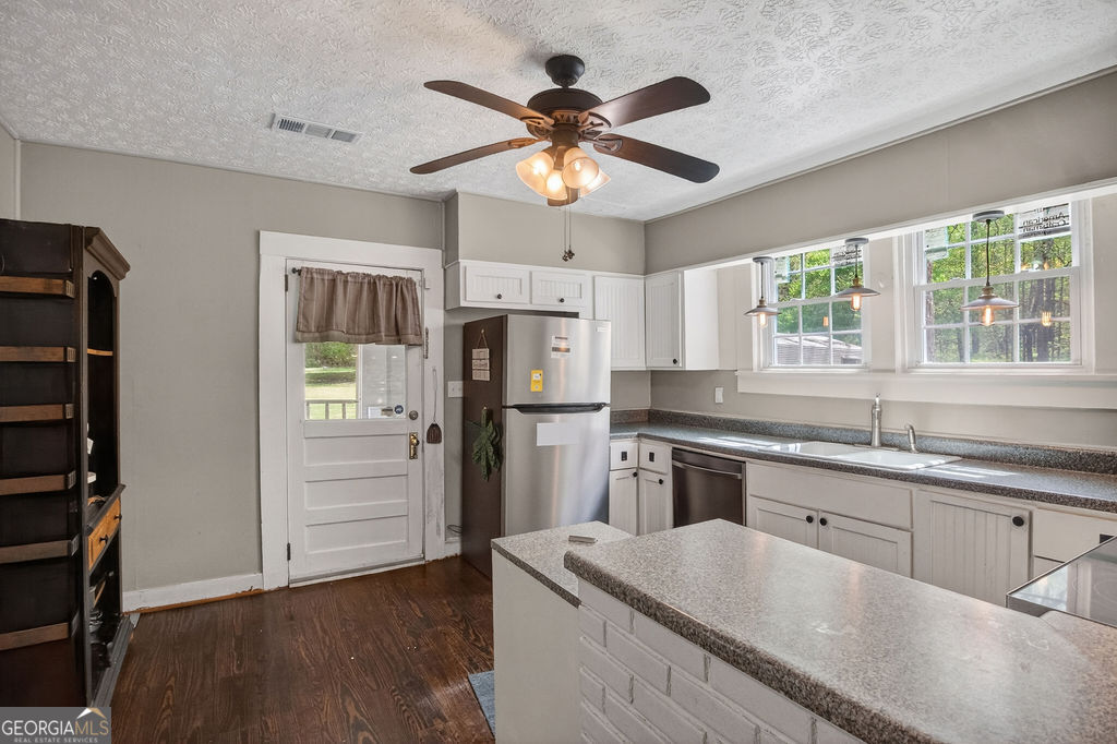 2051 Emmett Doster Road Northwest Monroe, GA 30656 - Photo 12 of 50 a kitchen with stainless steel appliances granite countertop a refrigerator a sink dishwasher a stove and white countertops with wooden floor