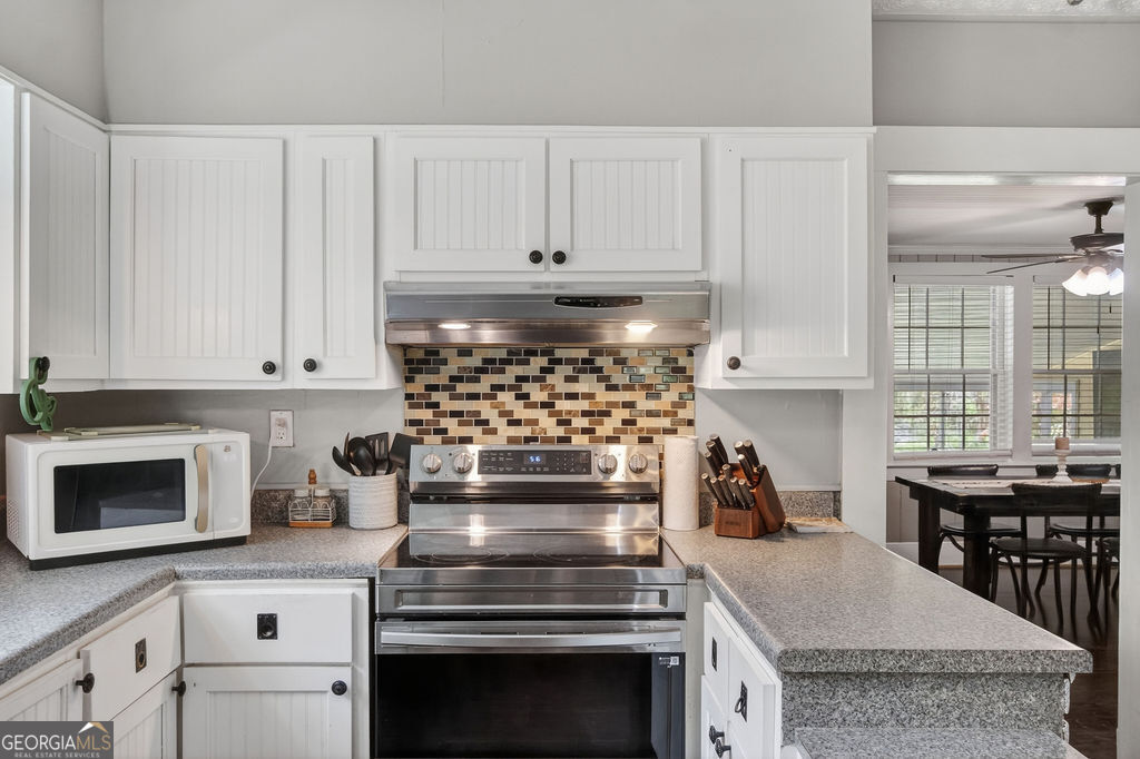2051 Emmett Doster Road Northwest Monroe, GA 30656 - Photo 13 of 50 a kitchen with granite countertop a stove oven and white cabinets