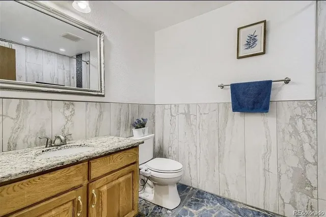 a bathroom with a granite countertop toilet a sink and a mirror