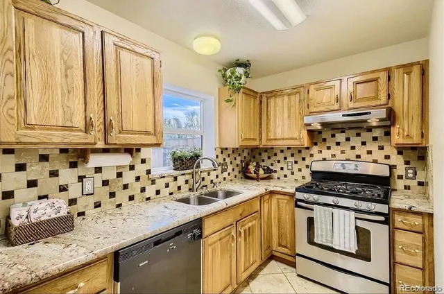 a kitchen with granite countertop a sink a stove and wooden cabinets