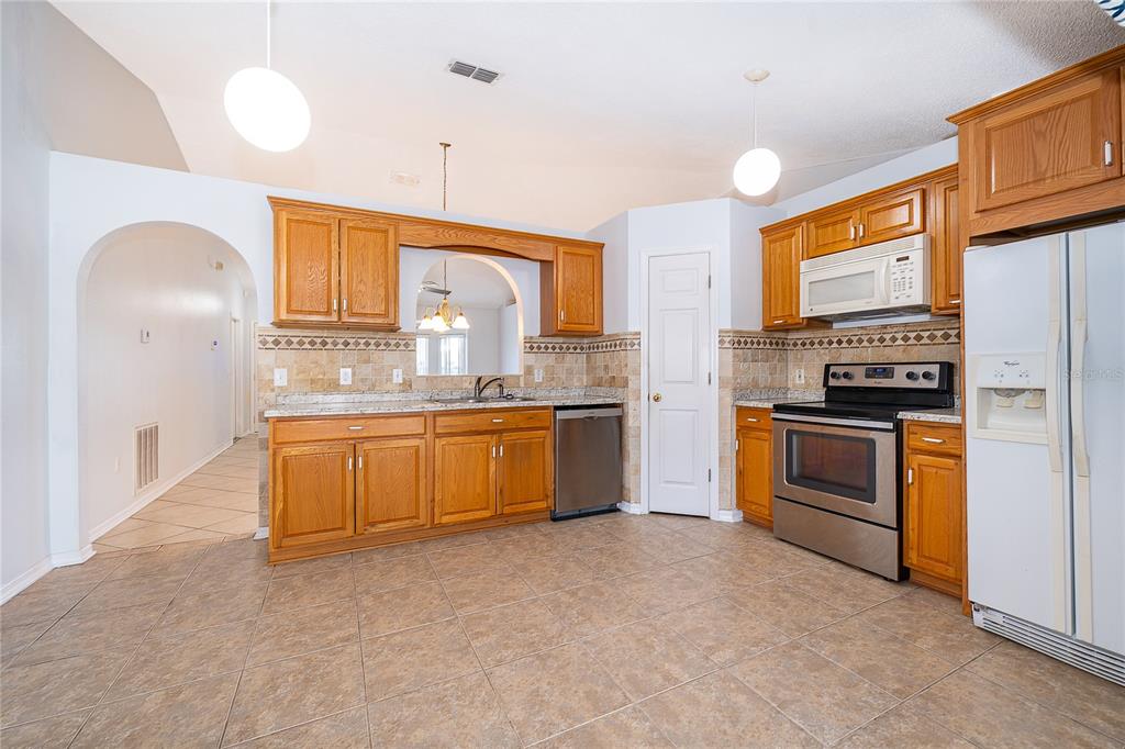 611 Baldwin Drive Kissimmee, FL 34758 - Photo 11 of 26 a kitchen with stainless steel appliances granite countertop a stove a sink and a refrigerator
